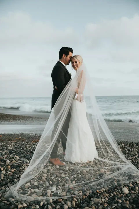 Çakıllı sahilde uzun duvaklı gelin ve damat