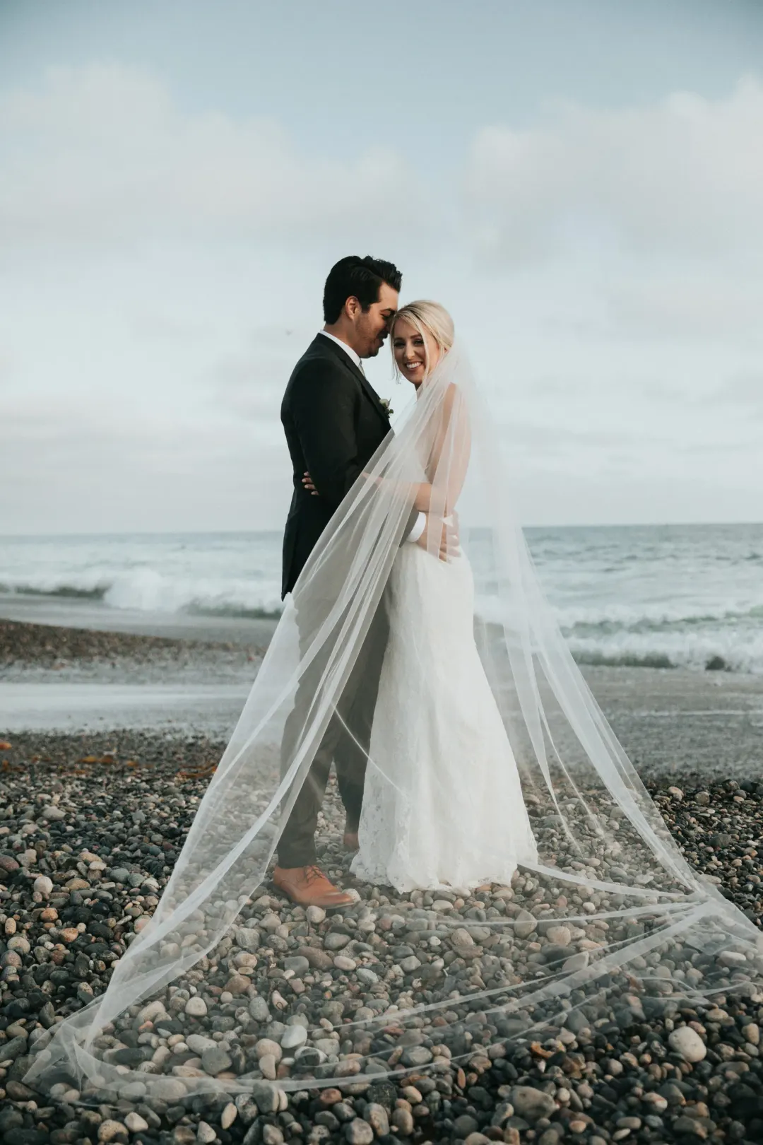 Çakıllı sahilde uzun duvaklı gelin ve damat